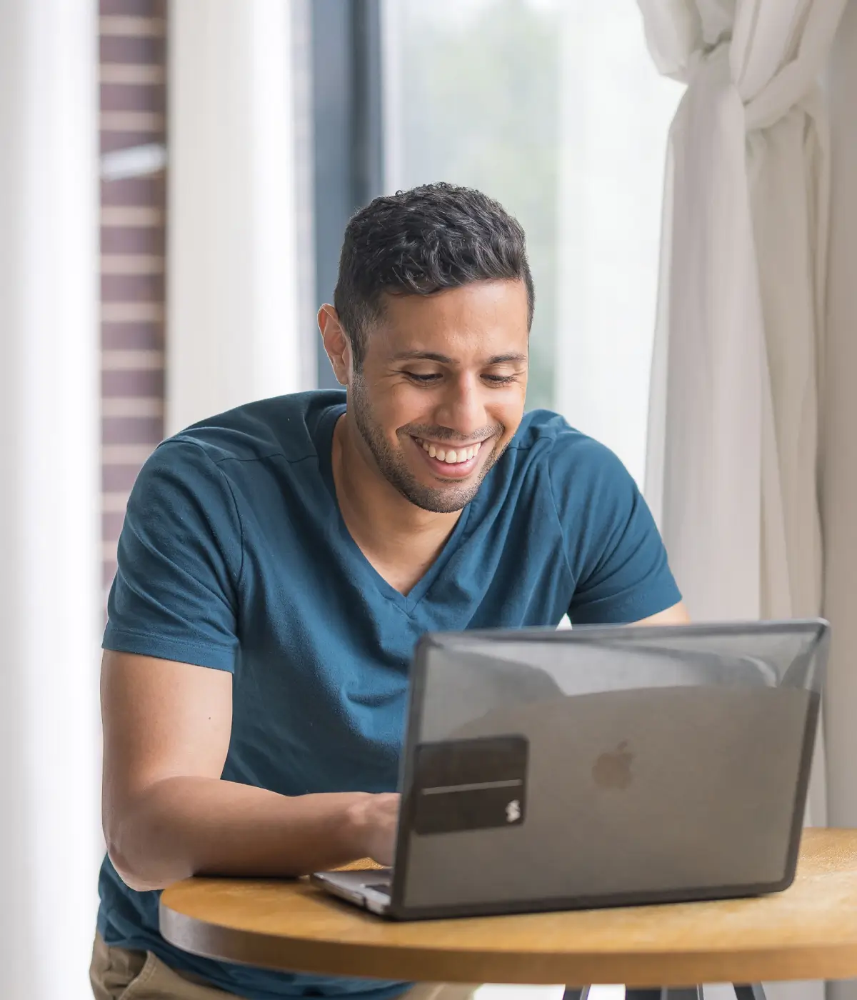 Collective member Elohim Pena looking at a laptop and smiling, Creative Director & Actor